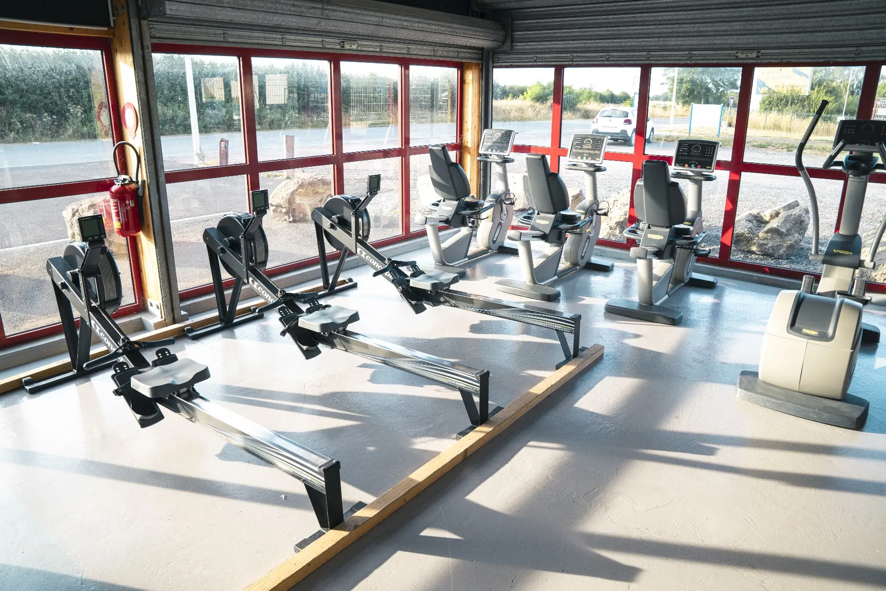 La salle cardio de Fitclub à Ouistreham, rameurs alignés devant de grandes baies vitrées