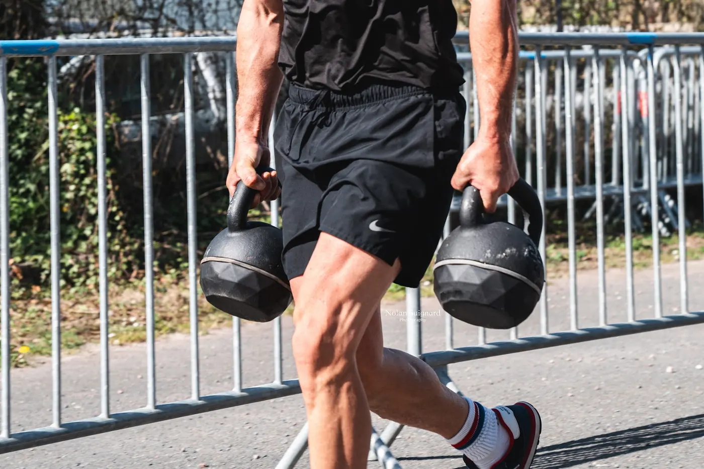 Sportif portant deux kettlebells à l'extérieur lors d'un événement Fitclub